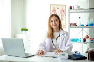 Female doctor working on laptop at office desk at in health clinic or hospital photo