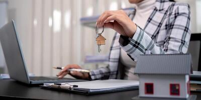 Real estate agent with house model and key photo