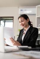 Young business woman asian or employee accounting bookkeeping documents checking financial data or marketing report working in office with laptop. Paperwork management photo