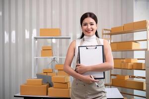 Young business woman asian working online ecommerce shopping at her shop. Young woman sell prepare parcel box of product for deliver to customer. Online selling photo