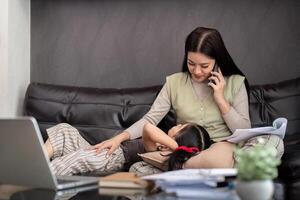 Business woman or mom working with her little daughter at a laptop. Freelance, work from home photo