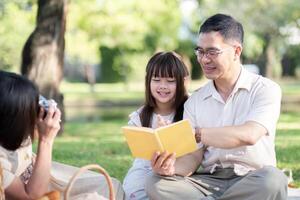 Grandparents enjoying with granddaughter in park and serenity. They are having joyful and cheerful time together. Loads of smile and happy moment photo