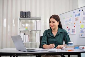 Businesswoman accountant using calculator and laptop for financial data saving in office room, Business financial, tax, accounting concept photo