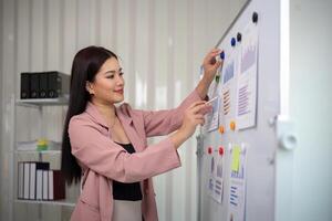 asiático mujer de negocios o hembra financiero analista financiero análisis y inversión plan en un tablero a oficina foto