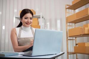 Young business woman asian working online ecommerce shopping at her shop. Young woman sell prepare parcel box of product for deliver to customer. Online selling photo