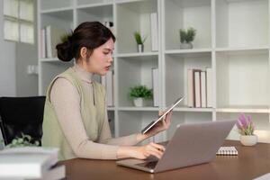 Happy beautiful asian woman relaxing using of laptop computer while sitting on table. Young creative girl working and typing on keyboard at home. work at home concept photo