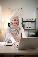 asiático musulmán mujer de negocios en hijab cabeza bufanda trabajando con papel documento en el moderno oficina. diversidad y oficina concepto foto