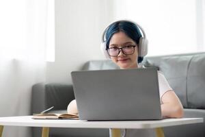 Happy young woman teenage wearing headphones writing note. student online learning class study online call zoom teacher with laptop and book photo