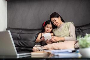 Business woman or mom working with her little daughter at a laptop. Freelance, work from home photo