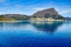 Island with rocks and trees in the fjord in front of the open sea in Norway. photo