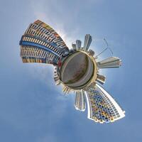 abstract swirling tiny planet spherical panorama of multi-storey buildings of skyscrapers of a residential complex in the form of a butterfly in blue sky photo