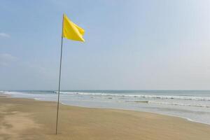 yellow flag on beach on sea or ocean as a symbol of danger. The sea state is considered dangerous and swimming is not prohibited. photo