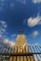 sillhoette of stone grave cross against the background of a blue evening sky with clouds photo