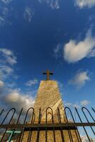 sillhoette of stone grave cross against the background of a blue evening sky with clouds photo