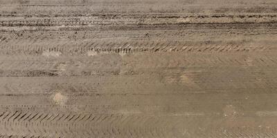 panorama of road from above on surface of gravel road with puddles and car tire tracks photo