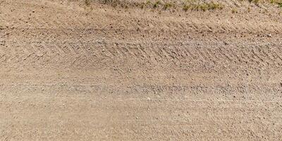 ver desde encima en textura de mojado lodoso la carretera con tractor neumático pistas en campo foto