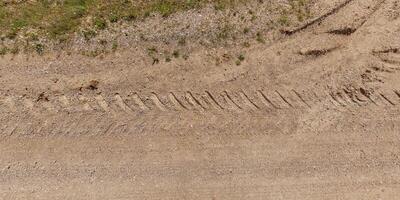 panorama of road from above on surface of gravel road with car tire tracks photo