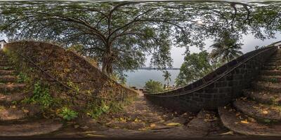 full hdri 360 panorama portuguese defensive abandoned military fortress with stone staircase on ocean with palm trees and banyan in equirectangular projection with zenith and nadir. VR AR content photo