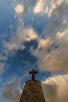 sillhoette of stone grave cross against the background of a blue evening sky with clouds photo