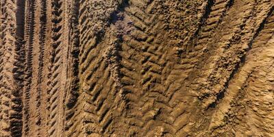 view from above on texture of wet muddy road with tractor tire tracks in countryside photo