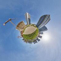 abstract swirling tiny planet spherical panorama of multi-storey buildings of skyscrapers of a residential complex in the form of a butterfly in blue sky photo