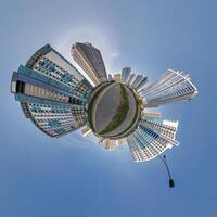abstract swirling tiny planet spherical panorama of multi-storey buildings of skyscrapers of a residential complex in the form of a butterfly in blue sky photo