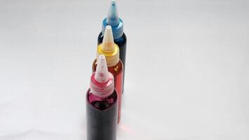 three different colored ink bottles are lined up on a white surface photo