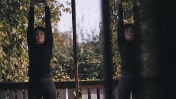 joven mujer haciendo calentar en terraza. levanta su manos arriba. en reflexión. ejercicio. ejercicio. video