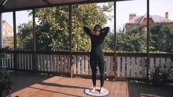 Young woman doing warm-up on terrace. raises his hands up. Workout. Exercise video