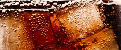 Cola with Ice. Close up of the ice cubes in cola water. Texture of carbonate drink with bubbles in glass. Cola soda and ice splashing fizzing or floating up to top of surface. Cold drink background. photo