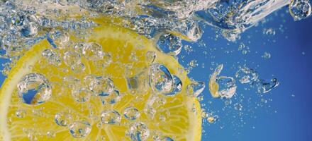 Underwater lemon slice in soda water or lemonade with bubbles. photo