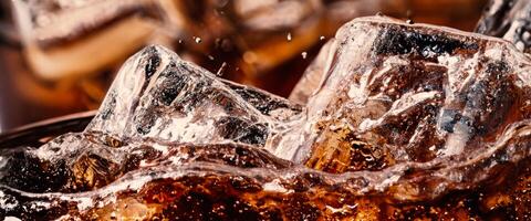 Splashing of Cola and Ice. Cola soda and ice splashing fizzing or floating up to top of surface. Close up of ice in cola water. Texture of carbonate drink with bubbles in glass. Cold drink background photo