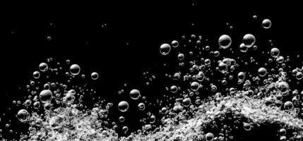 Soda water bubbles splashing underwater against black background. photo