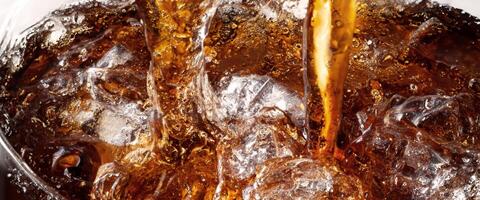 Cola soda and ice splashing fizzing or floating up to top of surface photo