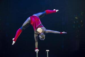 A gymnast performs in a show. A girl gymnast performs a circus acrobatic performance. photo