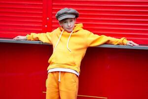 Happy boy in a vintage hat and orange suit posing at a red kiosk. photo