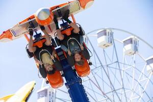Teenagers ride head down on a carousel. Extreme rides in the park. photo