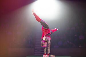 A gymnast performs in a show. A girl gymnast performs a circus acrobatic performance. photo