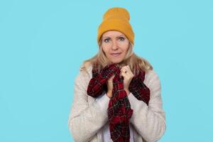 Adult beautiful woman in warm winter clothes on a blue background. photo