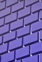 Decorative concrete wall with a relief similar to a large brick masonry painted in bright violet paint photo