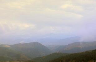 Morning view from the Dragobrat mountain peaks in Carpathian mountains, Ukraine. Cloudy and foggy landscape around Drahobrat Peaks photo