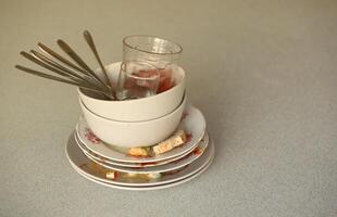 Stack of dirty dishes with food leftovers on the table after meal. Banquet ending concept. Unwashed dishes photo