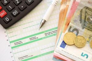 Filling german tax form process with pen and euro money bills close up. Tax paying period photo