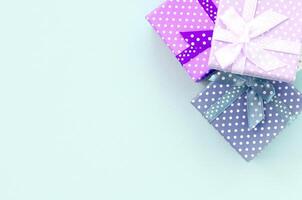 Pile of a small colored gift boxes with ribbons lies on a violet background. Minimalism flat lay top view photo