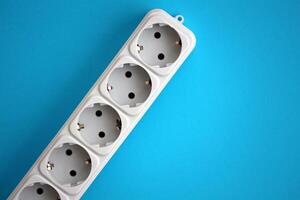 White electrical multi plug extender with european socket on bright blue background photo
