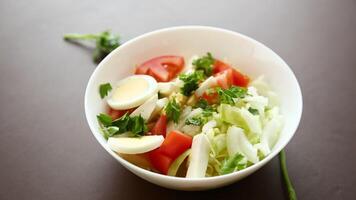 fresh vegetable salad, cabbage, tomatoes in a bowl on a wooden table video