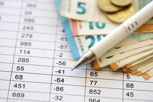 Business concept with many euro money bills and pen on schedules with calculations photo