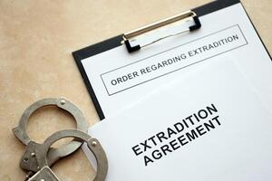 Extradition Agreement and Order Regarding Extradition with handcuffs on table photo