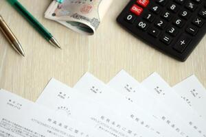 Japanese tax forms lies on table with calculator, pen and japanese yen money bills roll photo
