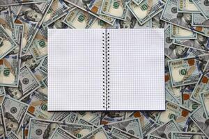 Office workplace table with blank notebook or notepad and many hundred dollar bills photo